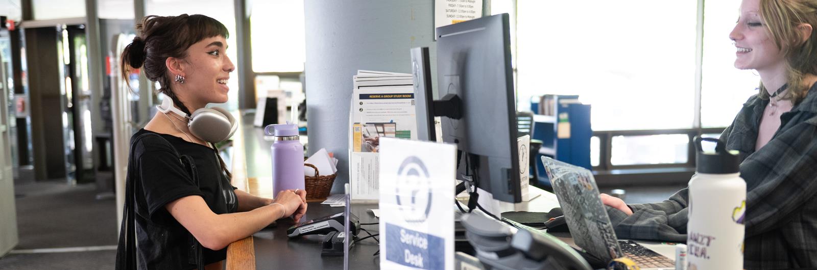 A student worker helps another student at the service desk in Hagerty Library