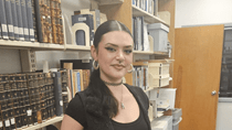 A woman stands next to shelves in the Archives Reading Room.