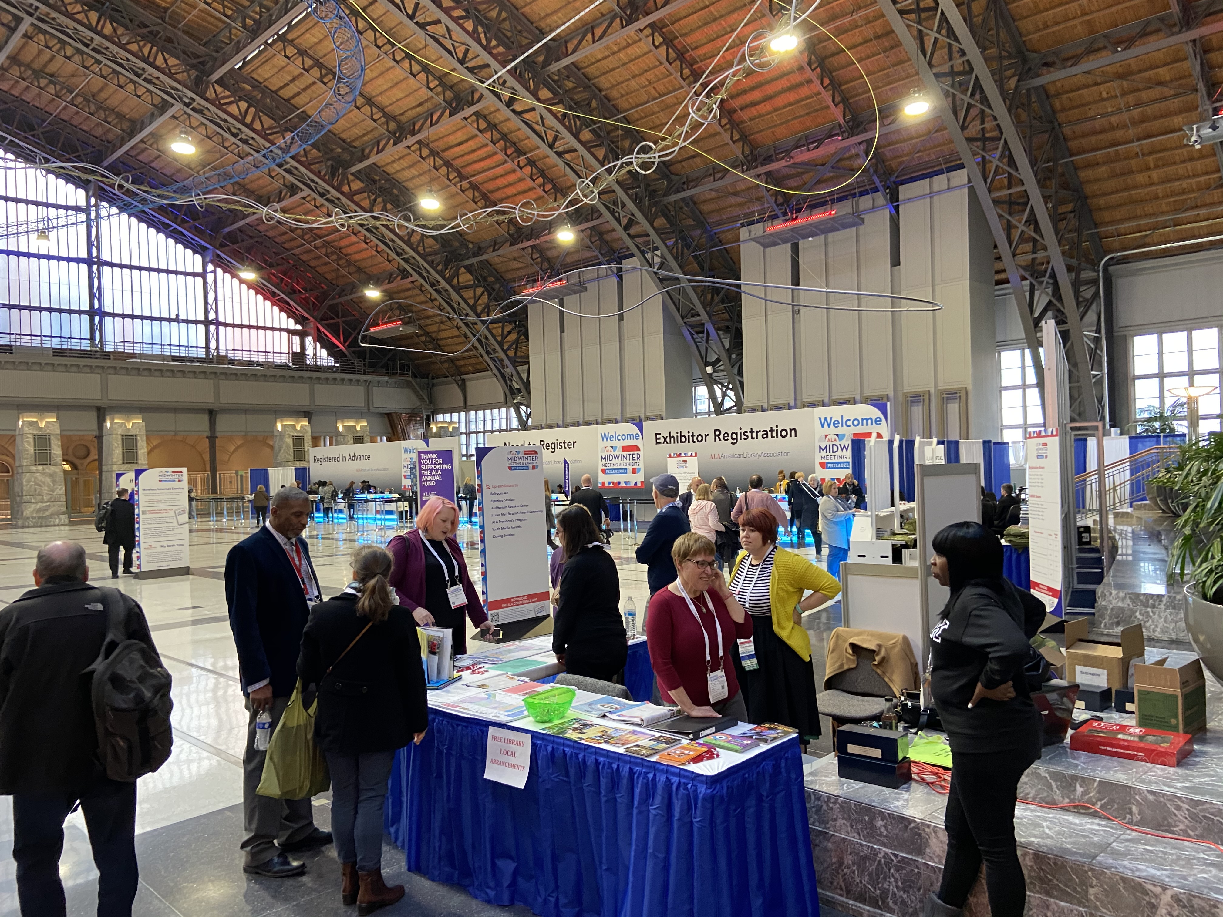 Men and women stand around a table in a large hall