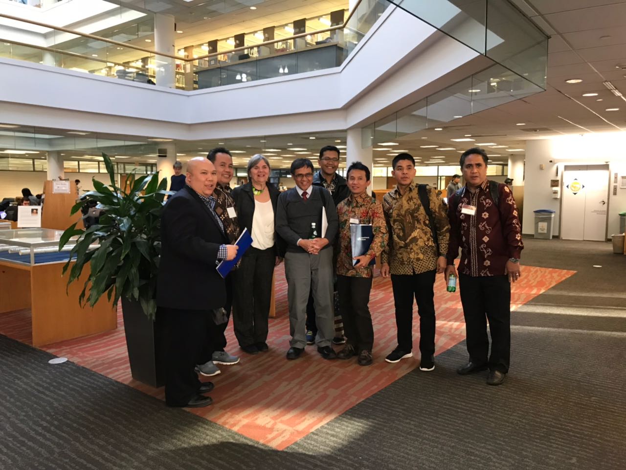 Seven men and one woman pose for a photo in the first floor of the W. W. Hagerty Library.