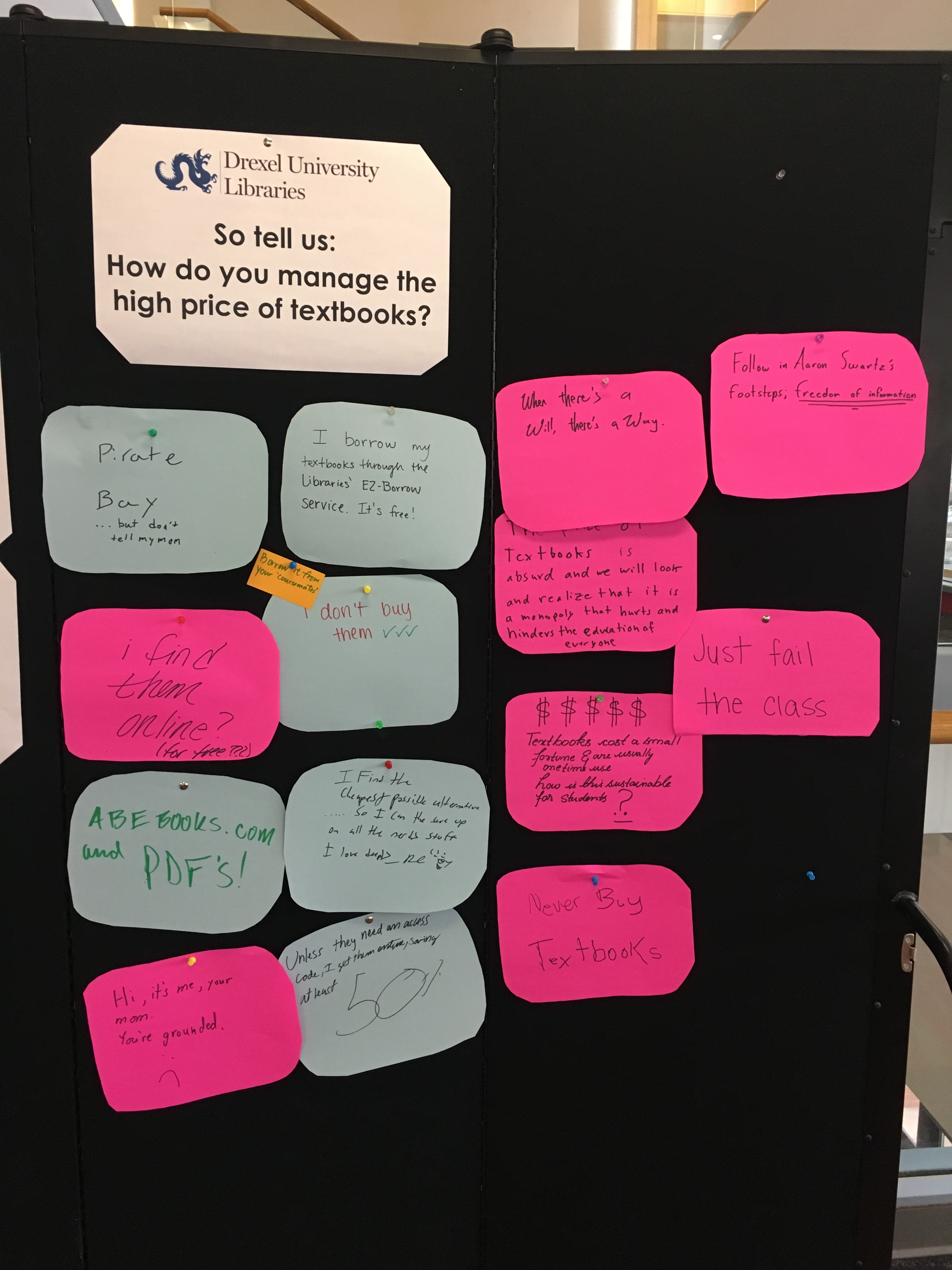 A black board covered with pink and blue circles of paper.