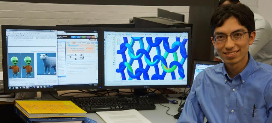 A man sits next to two computer screens