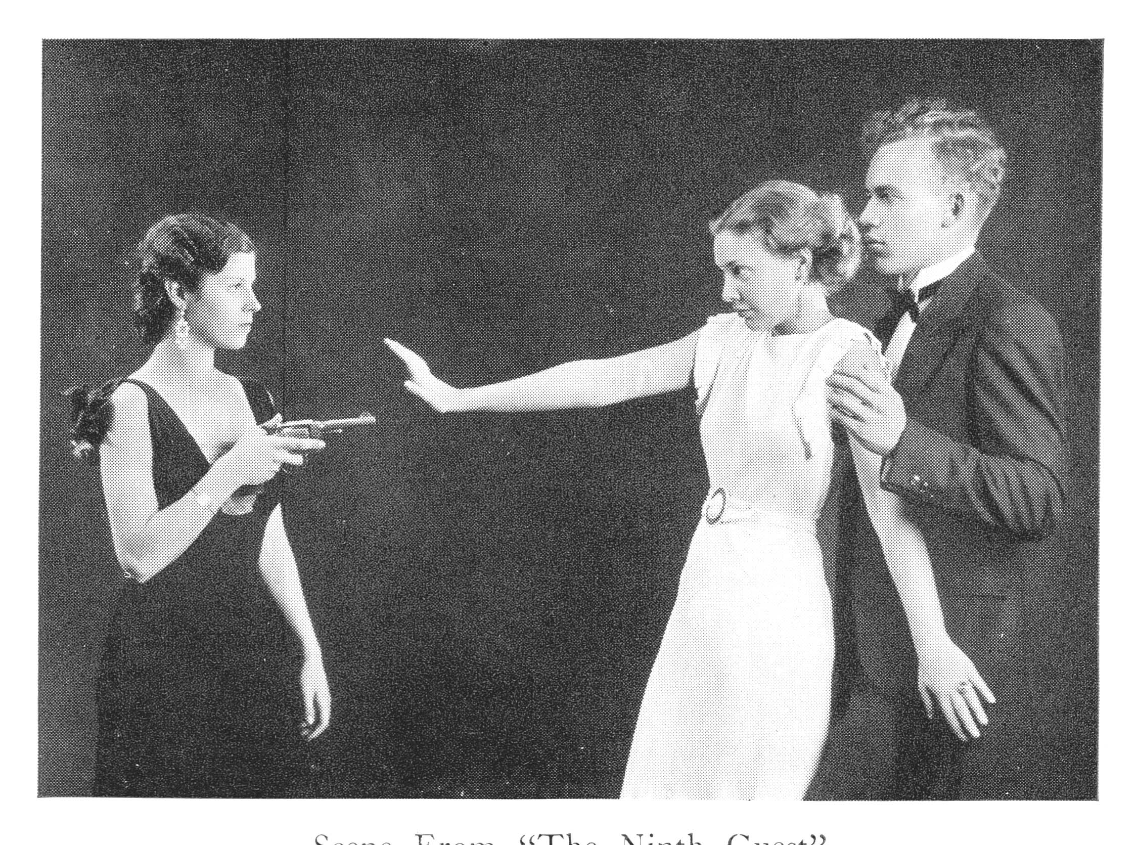 Two women and one  man act out a scene fro a play. One woman is pointing a gun at the other, while the man holds in place.