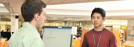 a library employee and a student talk at the circulation desk