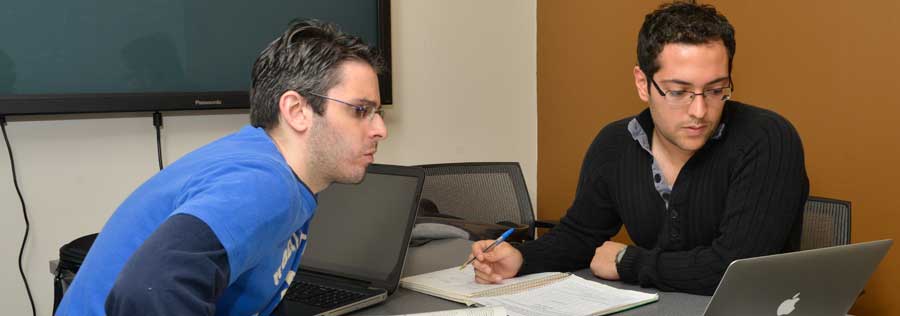 Two students collaborating on an assignment in a library study room.